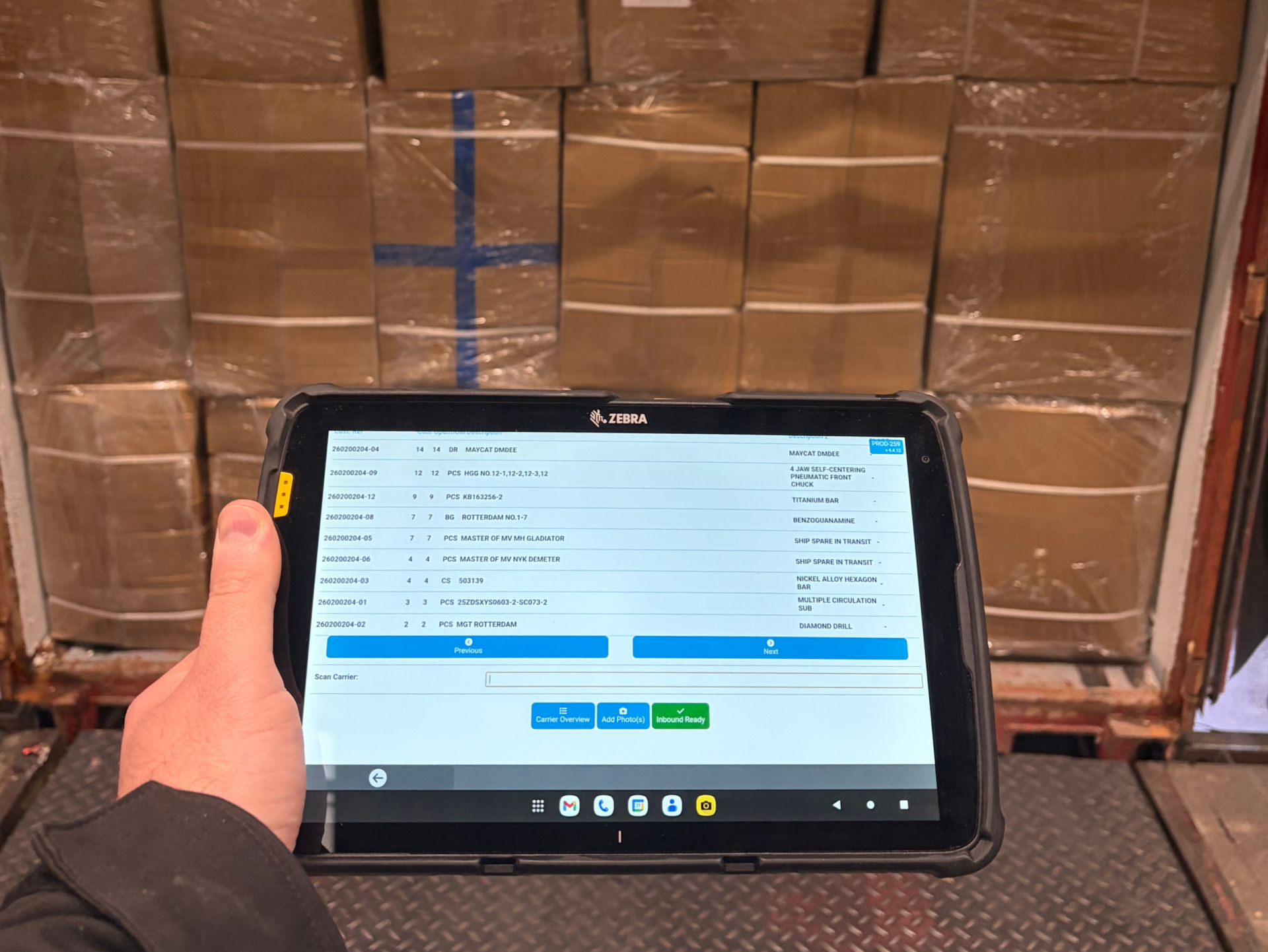 Person holding a tablet while standing in front of fully loaded container